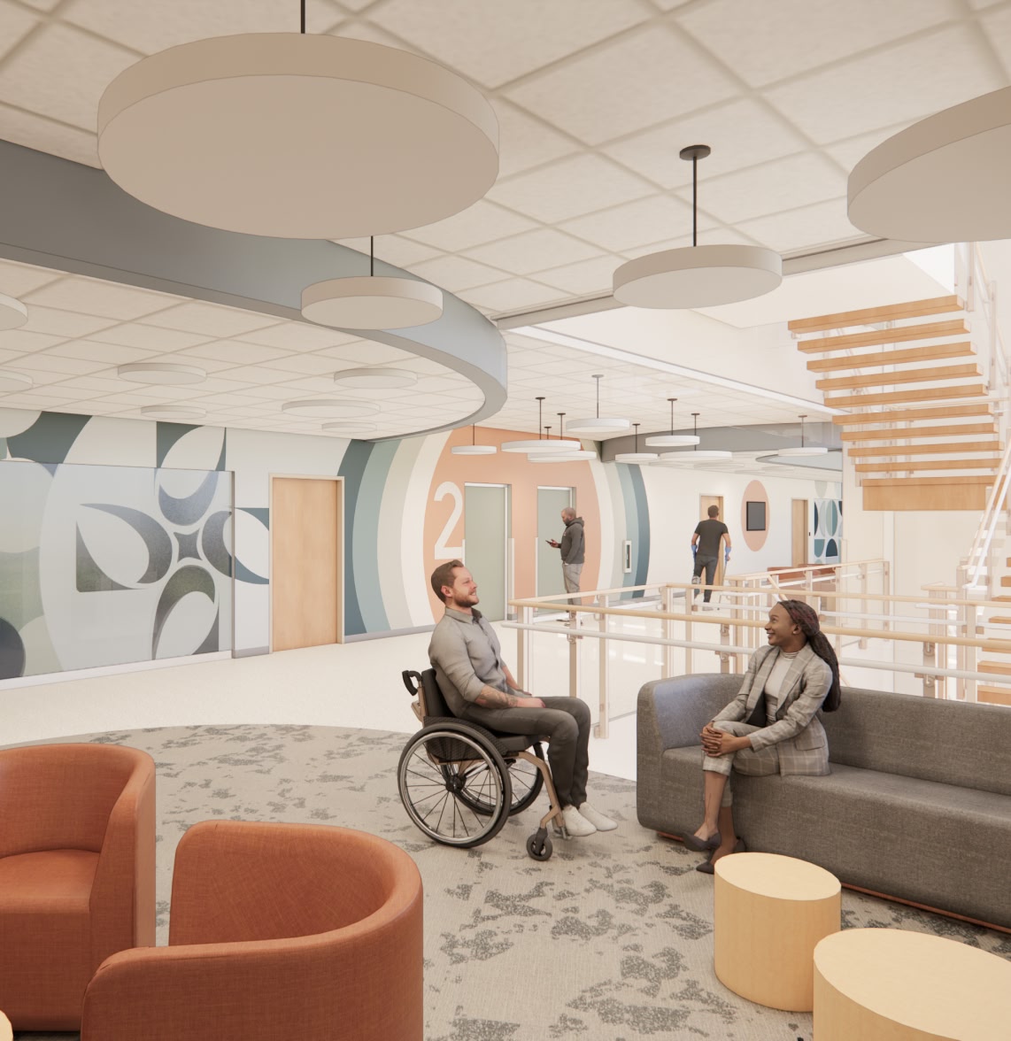 Modern lobby with vibrant wall art and circular patterns. A man in a wheelchair and a woman converse on a gray couch