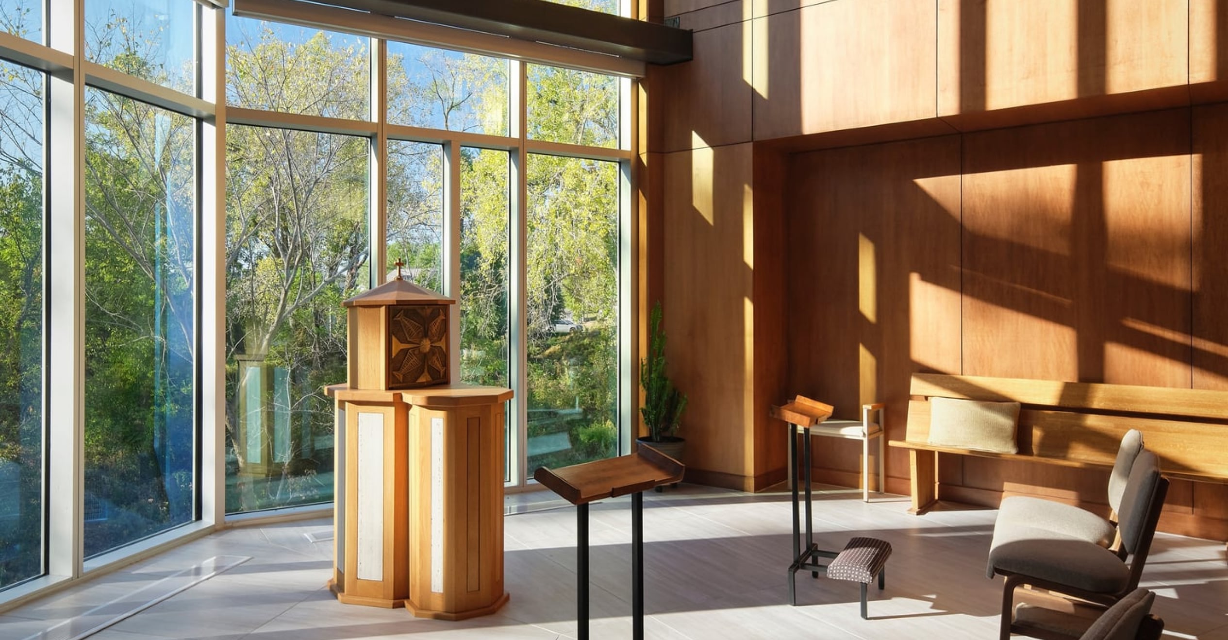 Bright, serene chapel interior with large windows, wooden accents, and simple seating