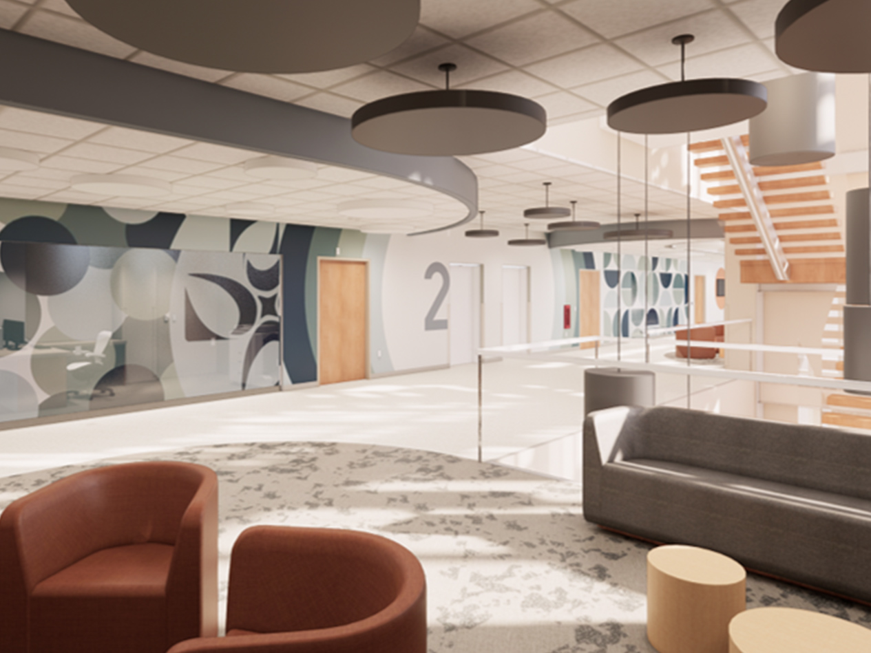 Concourse waiting area with lounge seating, patterned flooring, and an open stair connecting upper and lower levels.