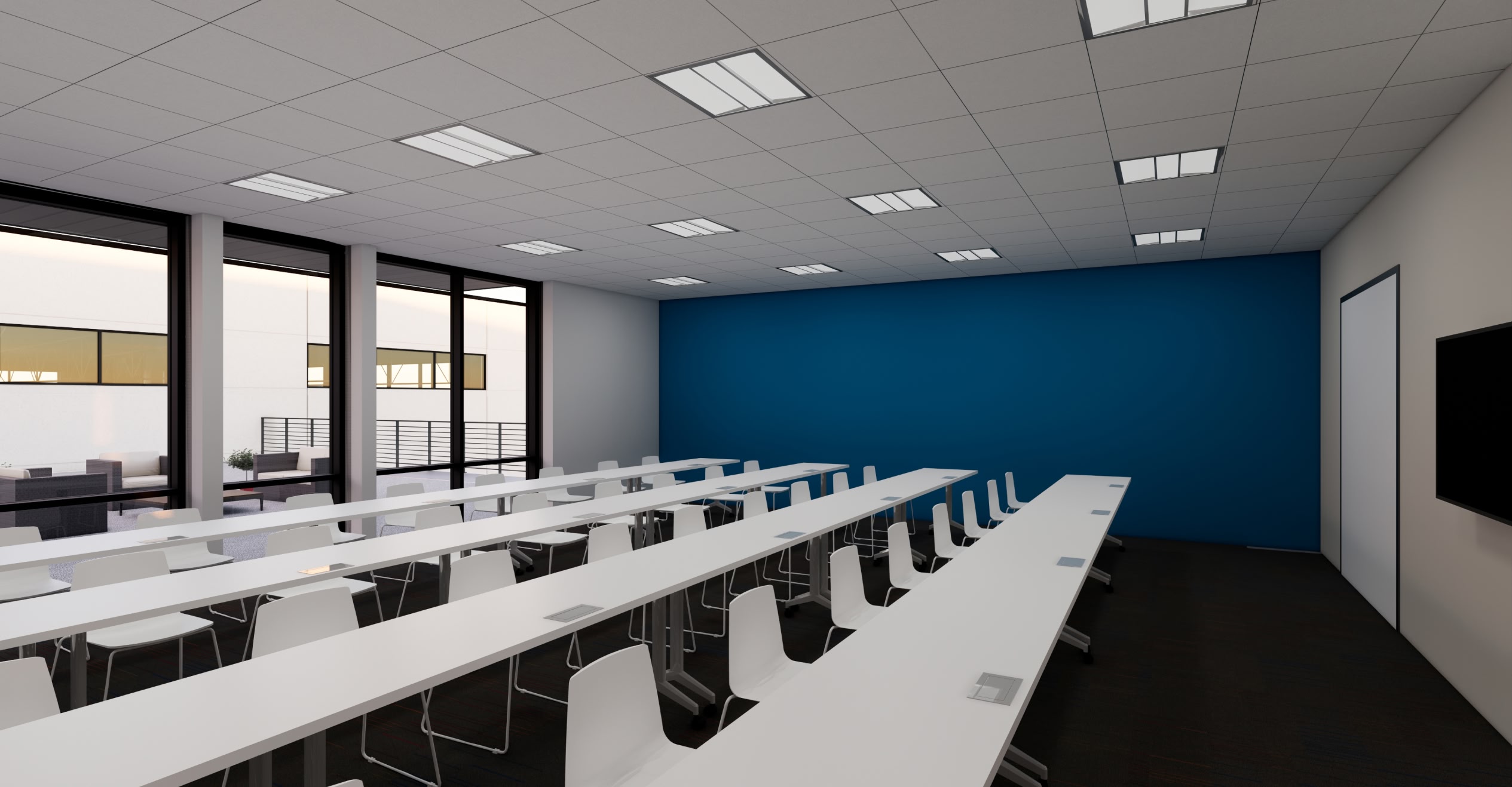 Modern classroom with two long white tables and white chairs, blue accent wall, ceiling lights, large windows on the left, and a wall-mounted screen.