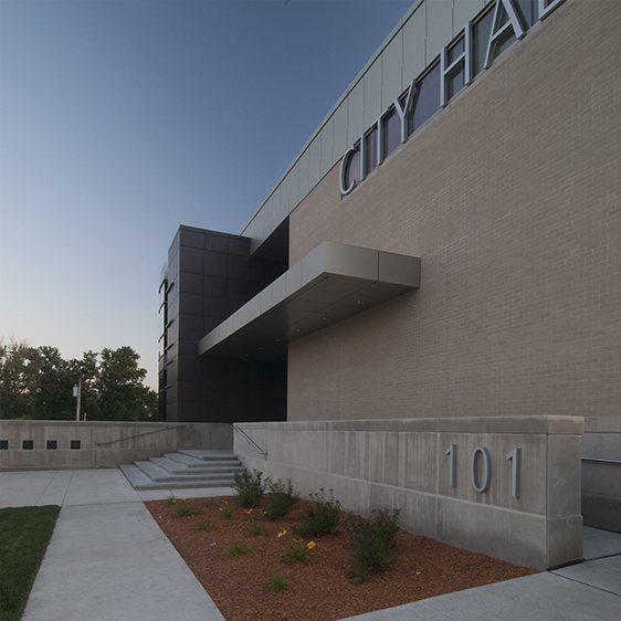 Exterior view of Hiawatha City Hall showing a modern civic building with glass curtain wall, metal panels, and landscaped site.