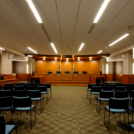 Interior public meeting room at the Jean Oxley Public Service Center featuring tiered seating, wood finishes, and integrated audiovisual systems.