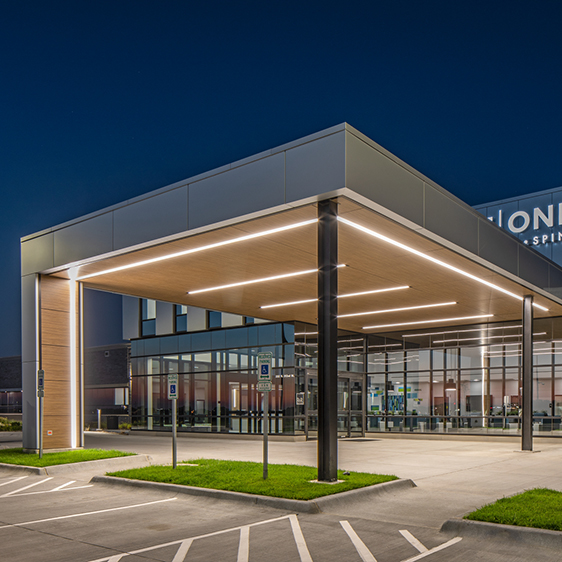 Exterior entrance of the MD West One Fountain Ridge medical office building at night with a covered canopy, glass facade, and illuminated signage.