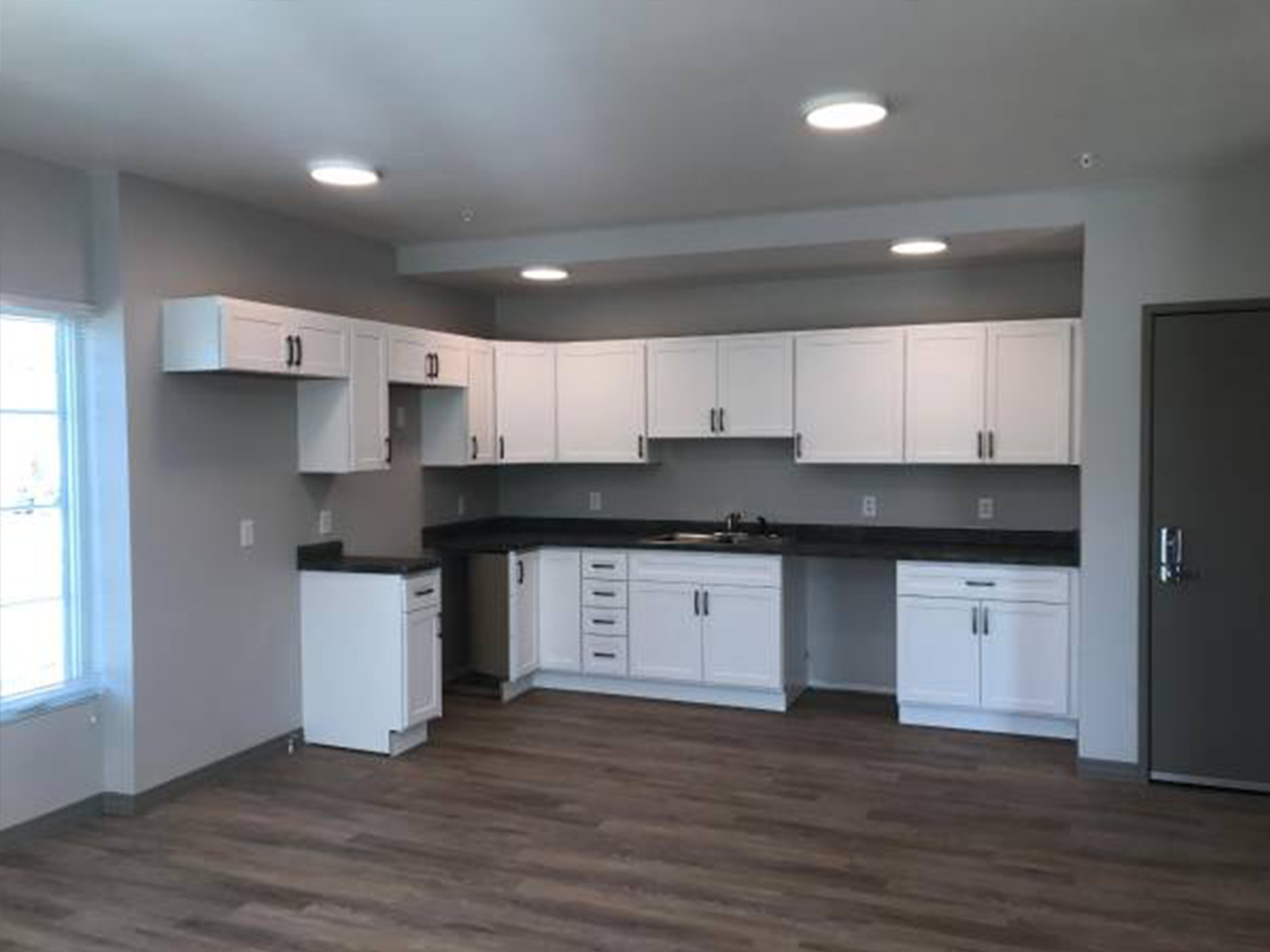 Completed apartment interior at The Heights showing a bright, modern kitchen with white cabinetry, updated lighting, and durable flooring following the adaptive reuse renovation.