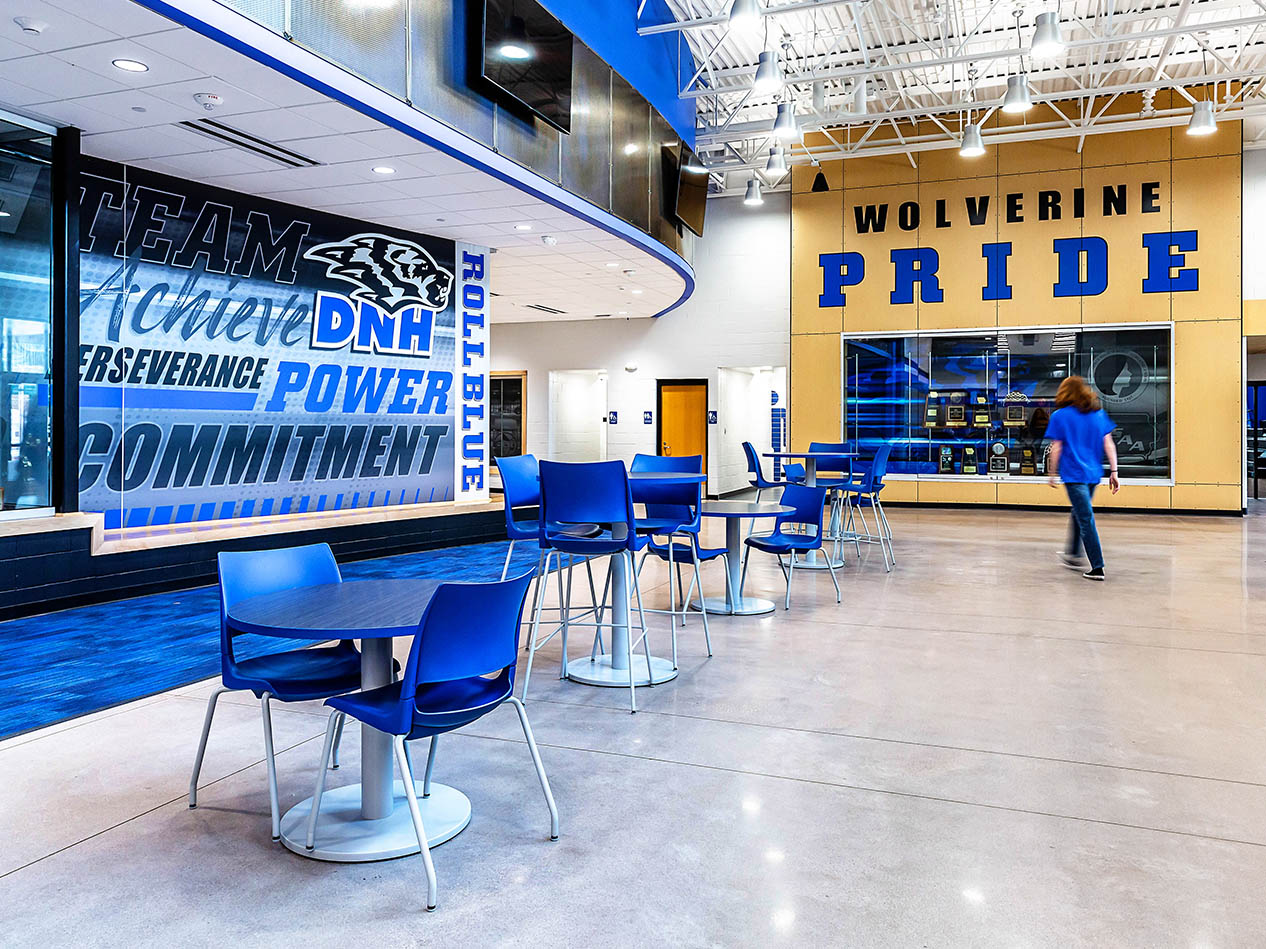 School commons area featuring DNH graphics, display screen, and accent lighting.