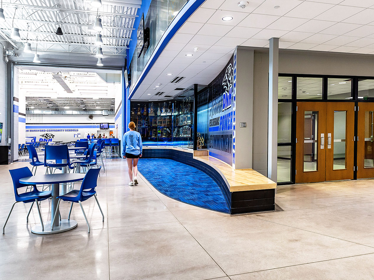 Common seating area with Wolverine Pride signage, blue seating, and bright overhead lighting.