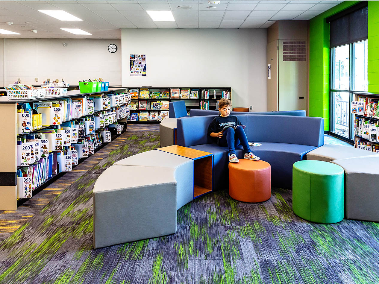 Library or media center with bookshelves, soft seating, and colorful lounge furniture.