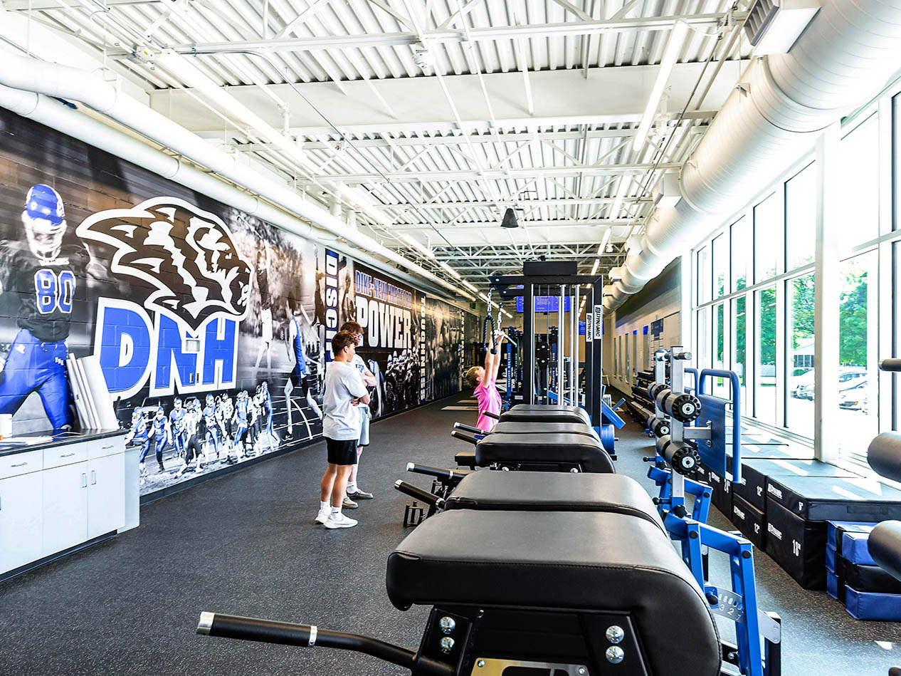 Fitness room with treadmills, weight equipment, and DNH wall graphics.