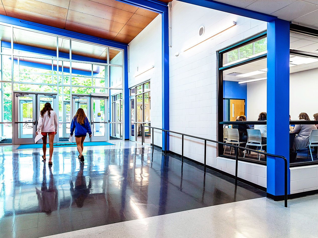 School hallway with polished floors, glass railing, and wood ceiling detail.