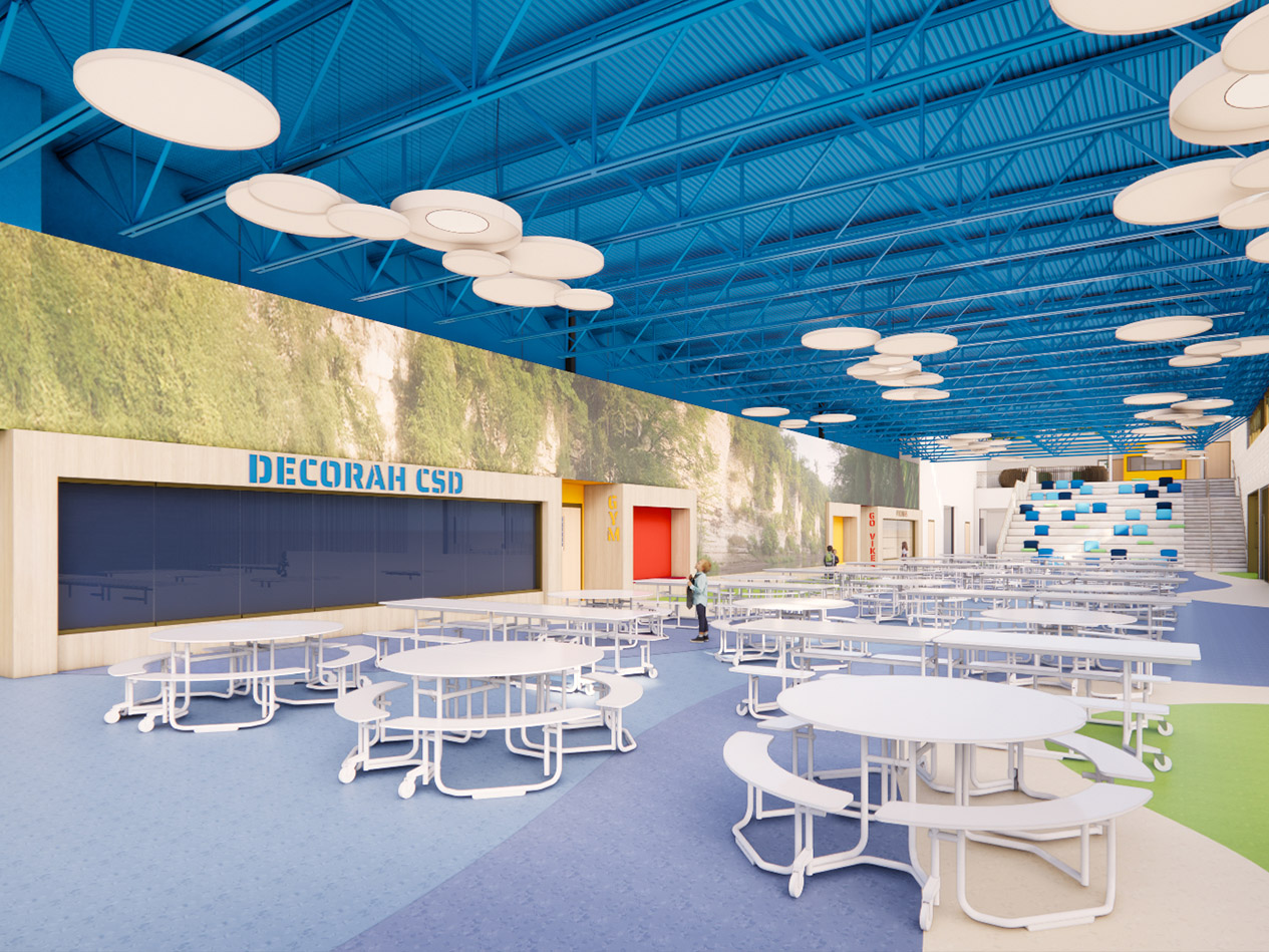 Elementary school commons and cafeteria with movable seating, high ceilings, acoustic panels, and Decorah CSD branding.