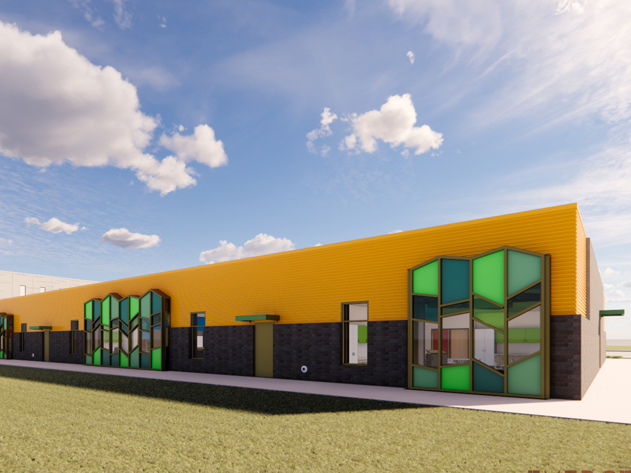 Exterior view of elementary school classroom wing with colorful panels, large windows, and yellow metal siding at Decorah Community School District.