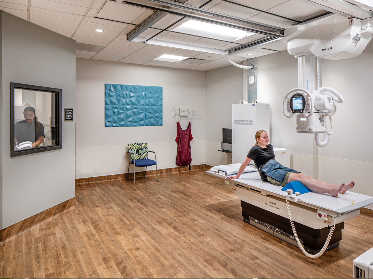 Patient in an imaging exam room at the MD West One Fountain Ridge clinic with advanced diagnostic equipment and wood-look flooring.