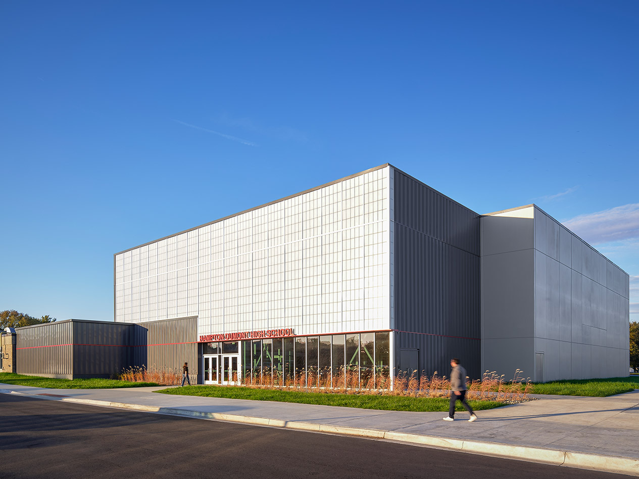 Angular exterior of modern school building with white cladding and clear blue sky.