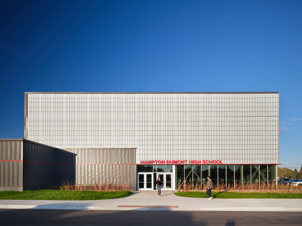 Exterior view of large school building with metal panel cladding and main entrance canopy.