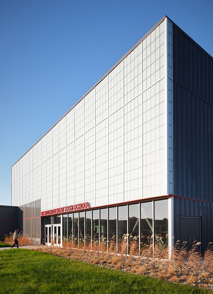 Contemporary school exterior with white metal panels and red accent detailing.