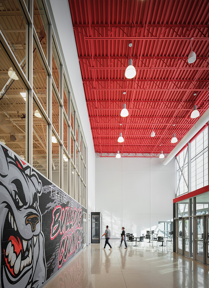 Interior commons space with red exposed ceiling, large windows, and seating areas.