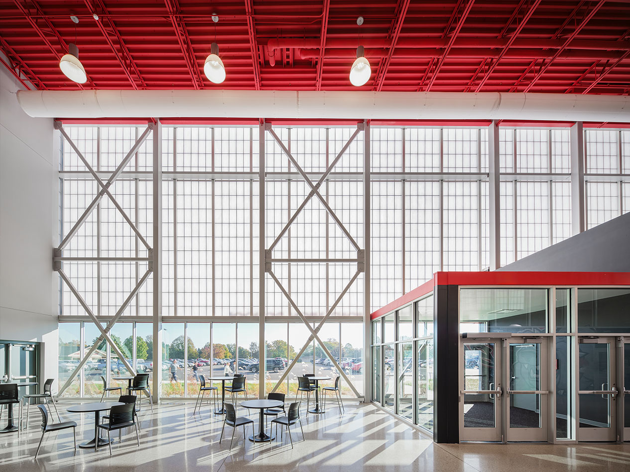 Two-story school commons with glass curtain wall and red ceiling structure