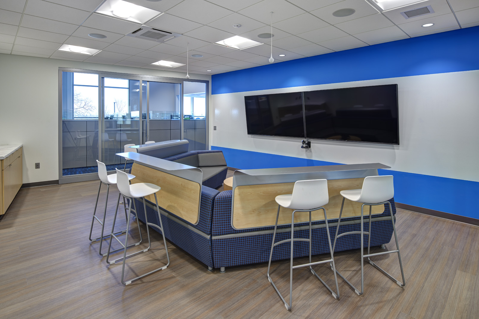 Technology-enabled collaboration space with lounge seating and presentation screen.