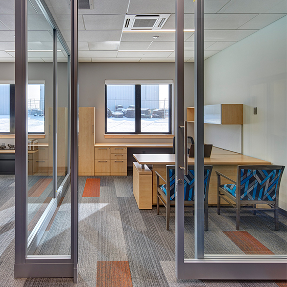 Glass-front private offices at The Accel Group headquarters designed to balance individual focus work with workplace transparency and collaboration.