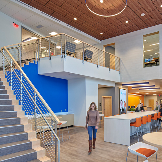 Open two-story lobby at The Accel Group headquarters featuring a central staircase, collaborative seating, and flexible gathering spaces.