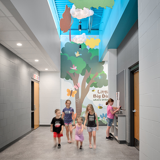 Children walking through the Riceville Daycare Addition corridor beneath playful ceiling features